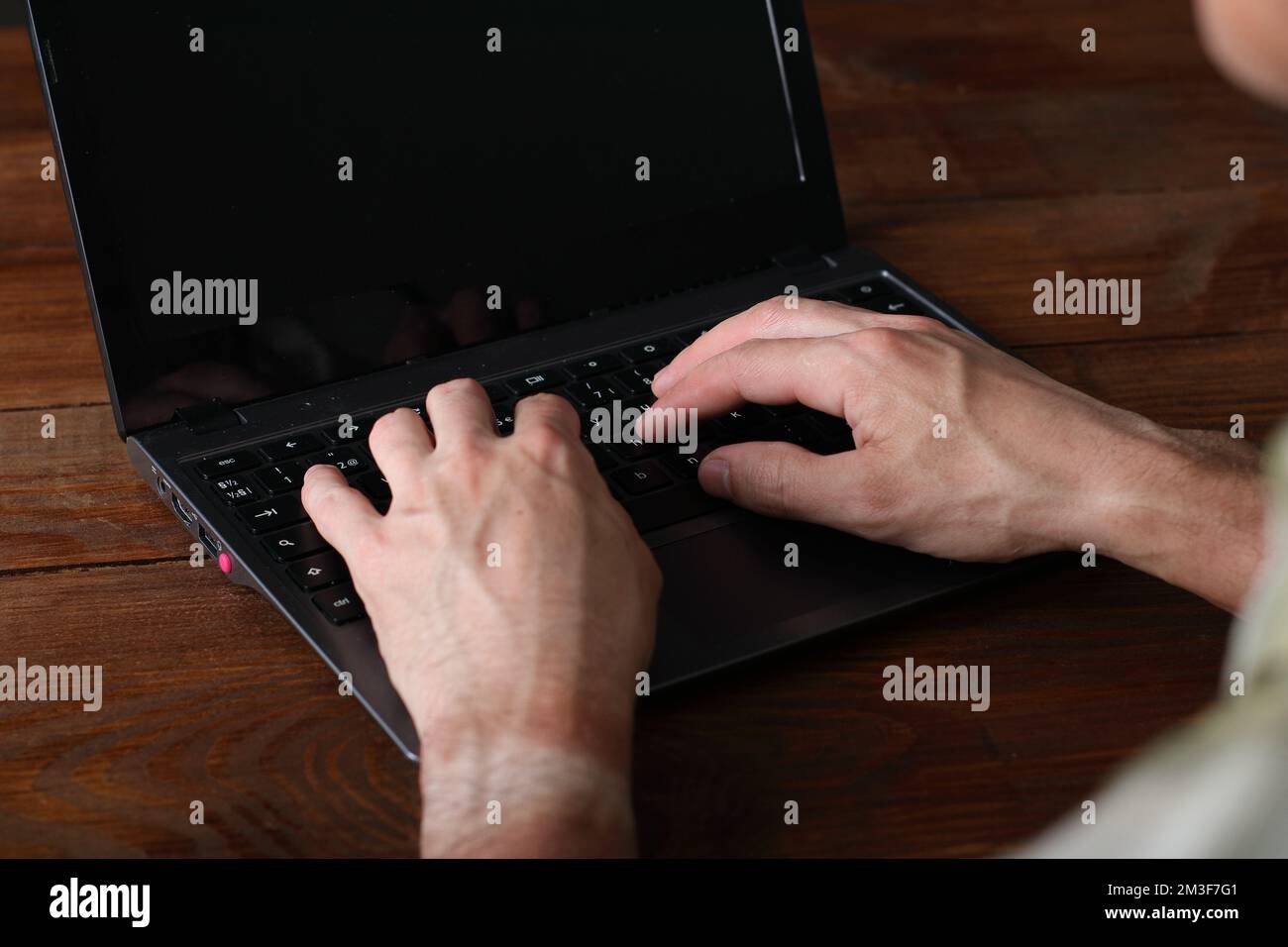 Person, die auf einer Computertastatur tippt und auf einem Holztisch steht Stockfoto