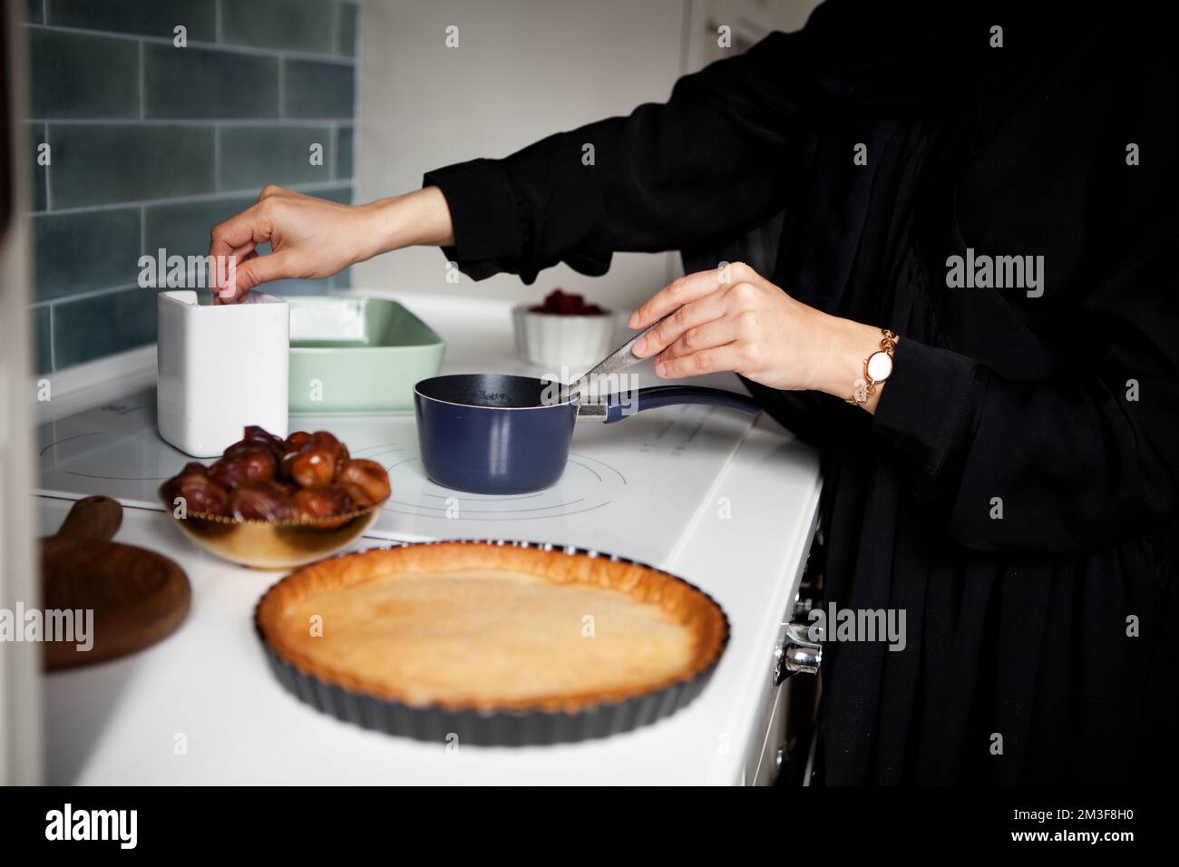 Eine Frau kocht Kuchen auf dem Herd. Die Hände schließen sich Stockfoto