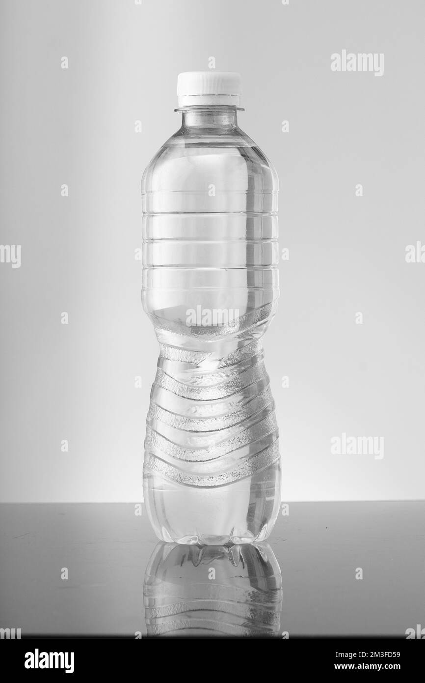 Kleine Flasche ohne Farbwasser auf grauem Hintergrund Stockfoto