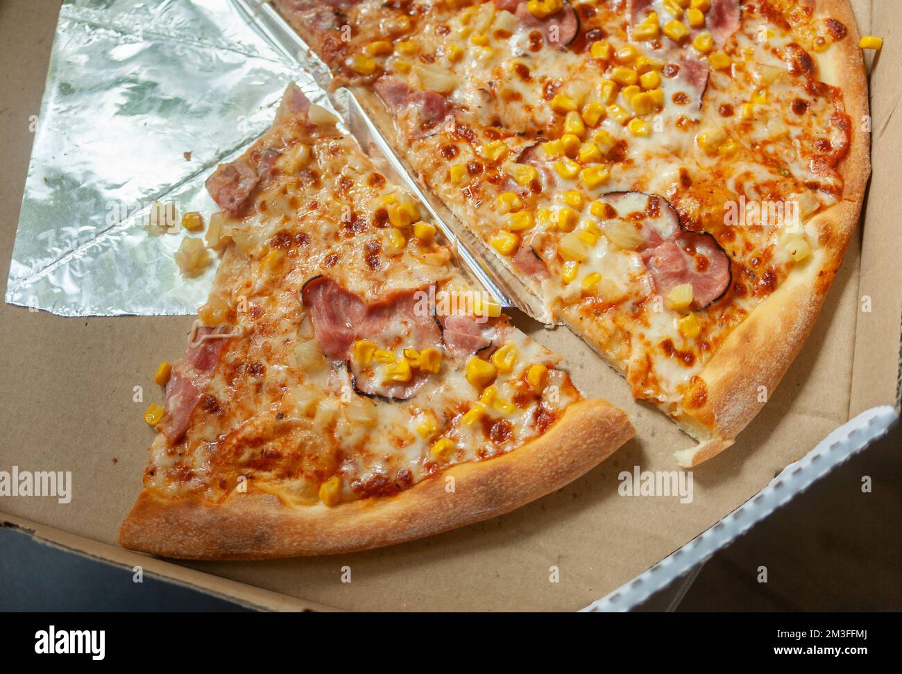 Pizzastücke mit Speck und Mais in einer offenen Pappschachtel, Draufsicht Stockfoto