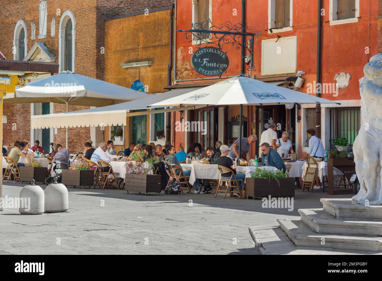 Restaurant piazza Italy, Blick im Sommer auf eine Gruppe von Menschen, die außerhalb einer Pizzeria im malerischen Hafen von Chioggia, Comune of Venice, Italien, essen Stockfoto