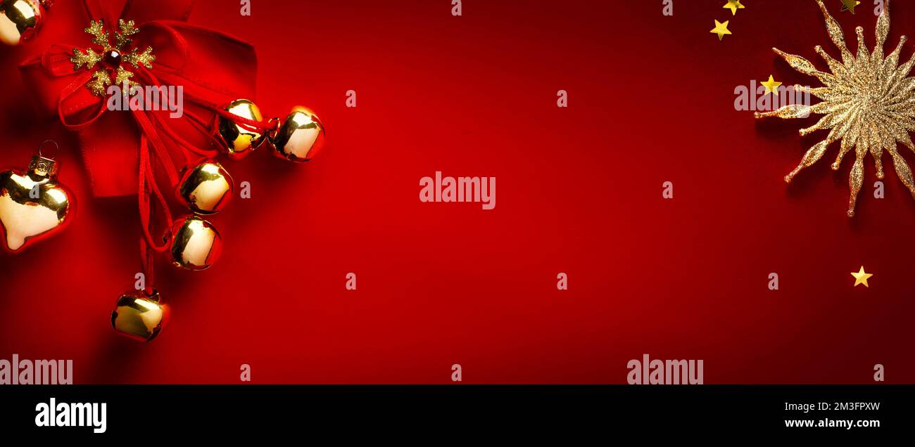 Weihnachtsgrußkarte oder Weihnachtsbanner; goldene Weihnachtsbaumschmuck auf rotem Hintergrund; Kopierbereich Stockfoto