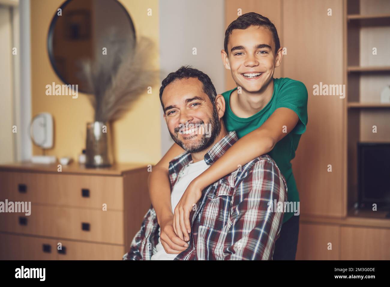 Porträt von glücklichem Vater und Sohn zu Hause. Sie umarmen sich. Stockfoto