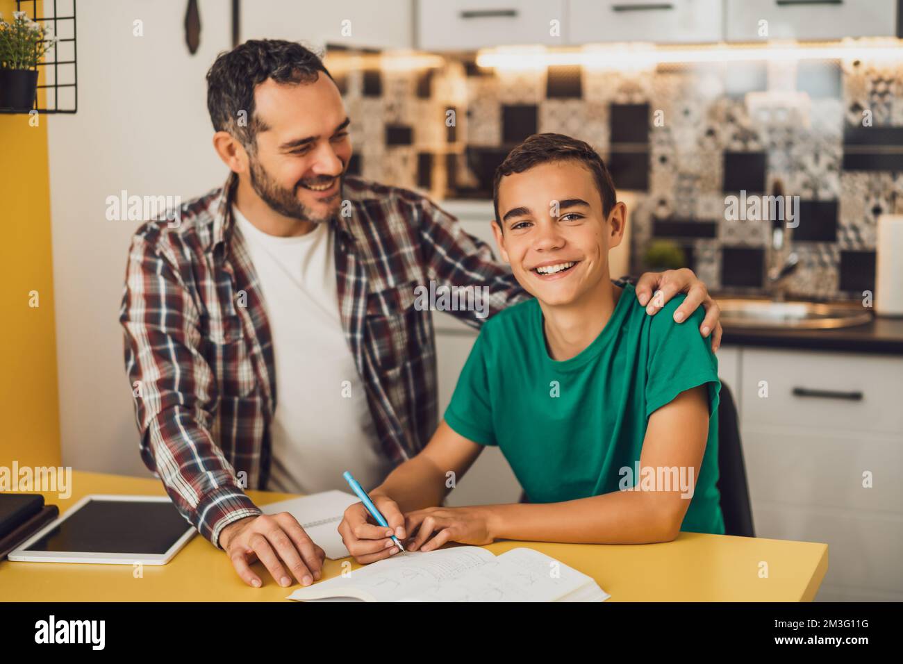 Vater hilft seinem Sohn beim Lernen. Sie machen Hausaufgaben zusammen. Stockfoto