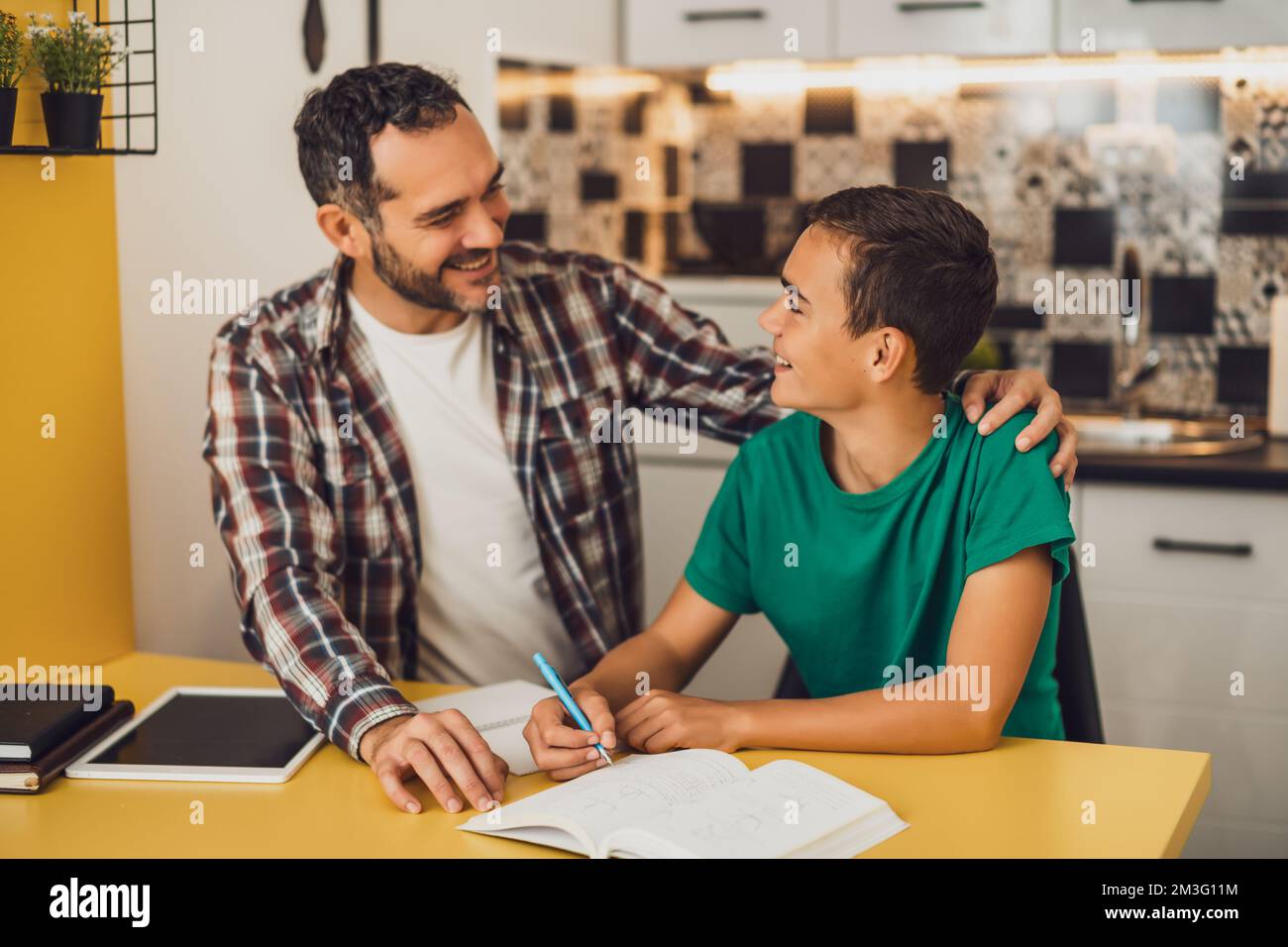 Vater hilft seinem Sohn beim Lernen. Sie machen Hausaufgaben zusammen. Stockfoto