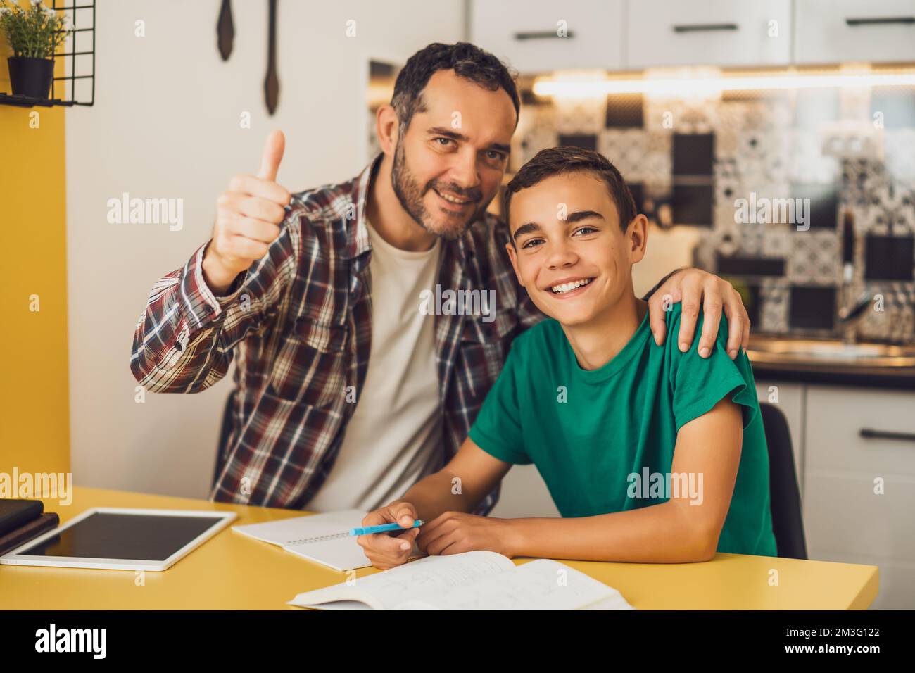 Vater hilft seinem Sohn beim Lernen. Sie machen Hausaufgaben zusammen. Stockfoto