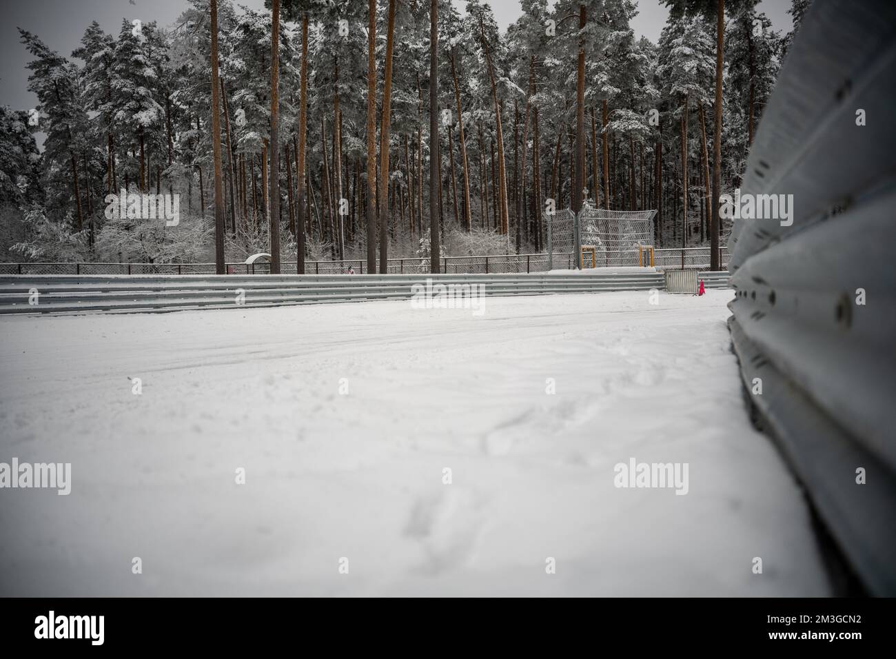 12-12-2022 Riga, Lettland ein verschneites Feld mit einem Zaun und Bäumen im Hintergrund und einem roten Hydranten im Vordergrund. . Stockfoto