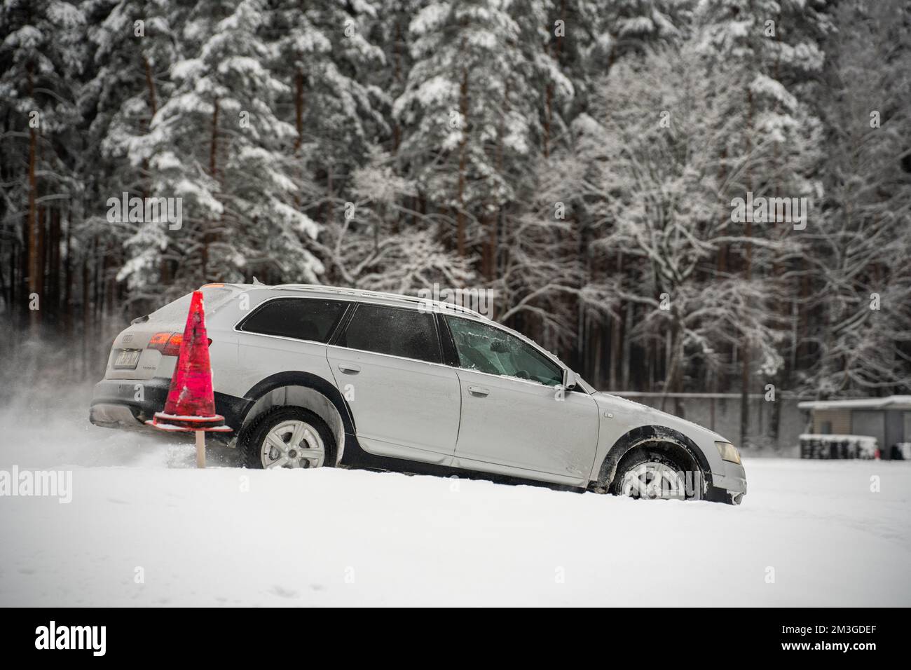 12-12-2022 Riga, Lettland ein weißes Auto, das im Schnee neben einem roten Feuerhydranten und Bäumen im Hintergrund mit Schnee auf dem Boden geparkt hat. . Stockfoto