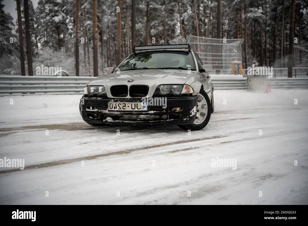 12-12-2022 Riga, Lettland ein Auto steht im Schnee neben einem Zaun und Bäumen im Hintergrund mit Schnee auf dem Boden. . Stockfoto