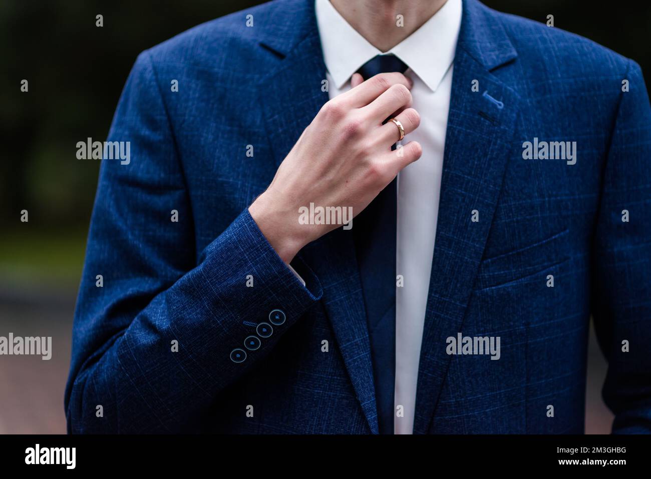 Eleganter Mann, der seine Krawatte über schwarzem Hemd bindet. Kabelbinder einstellen. Schwarz und Violett. Junger Geschäftsmann im Kostüm, isoliert auf schwarzem Hintergrund. Der Bräutigam passt sich an Stockfoto