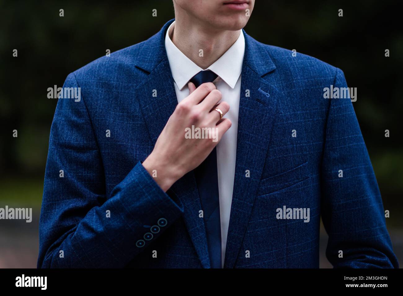 Eleganter Mann, der seine Krawatte über schwarzem Hemd bindet. Kabelbinder einstellen. Schwarz und Violett. Junger Geschäftsmann im Kostüm, isoliert auf schwarzem Hintergrund. Der Bräutigam passt sich an Stockfoto