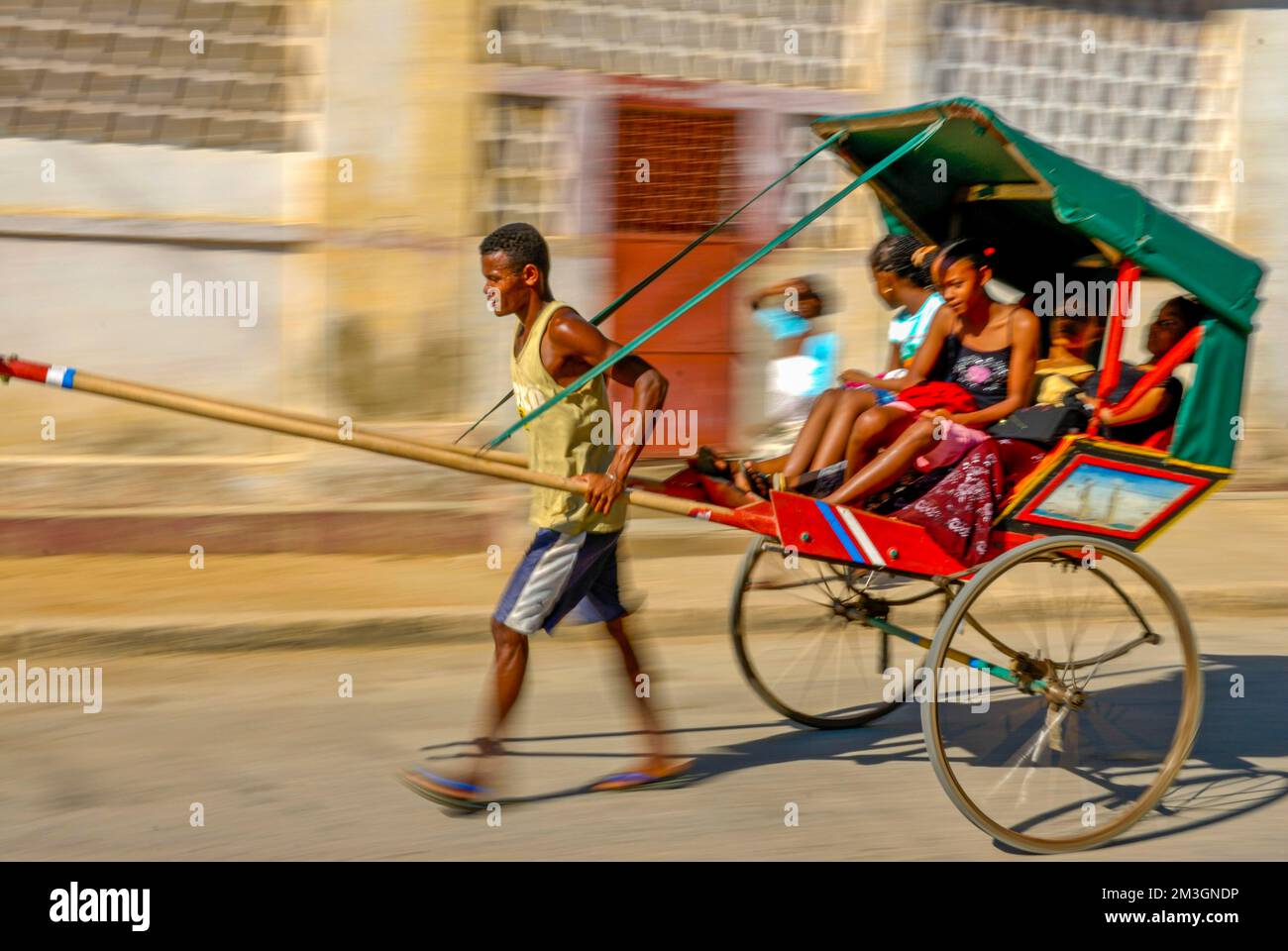 Ein Mann läuft mit seiner wandelnden Rikscha Toliara, Madagaskar Stockfoto
