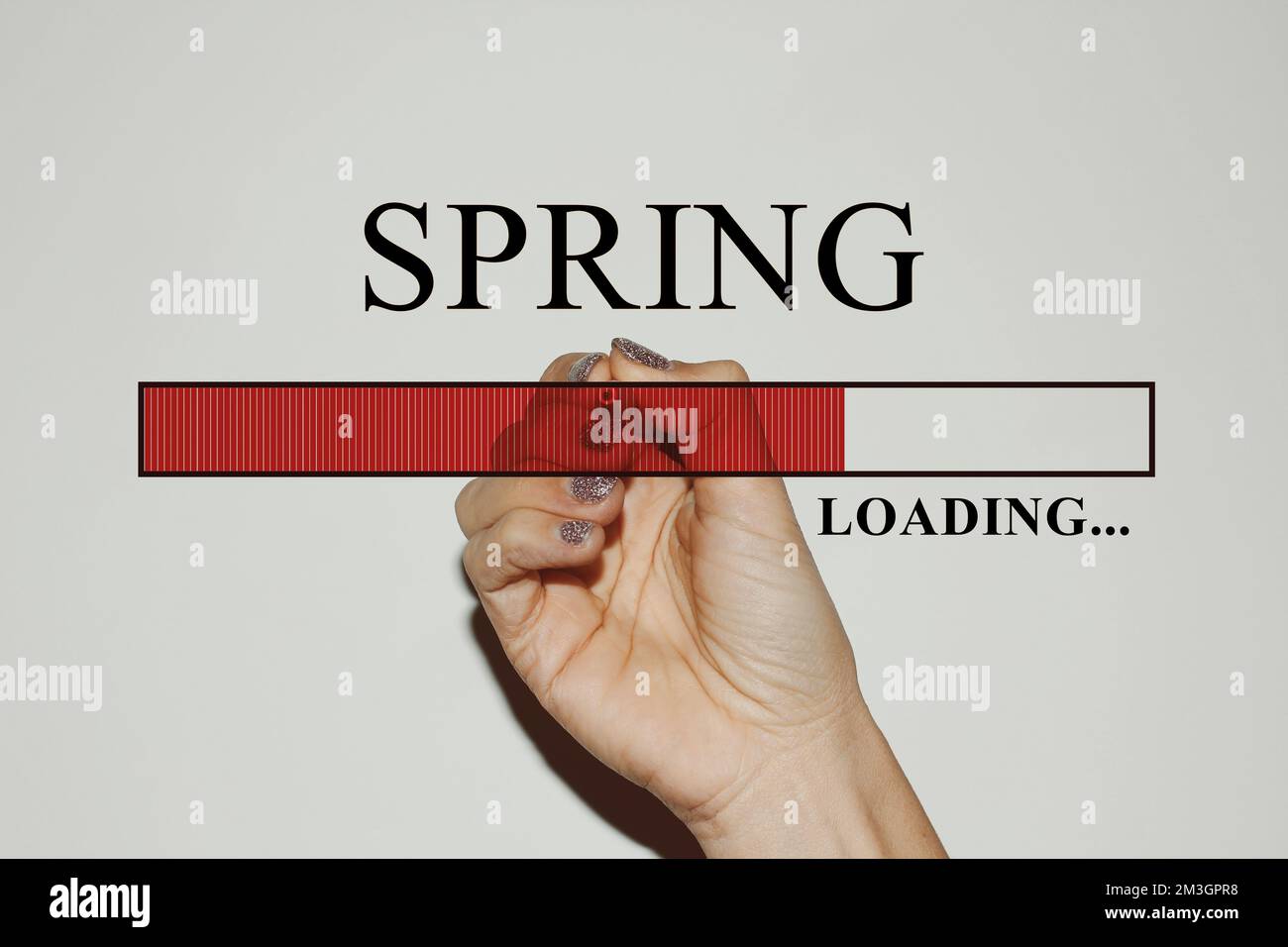 Weibliche Hand mit glitzernden Nägeln, die die Ladeleiste mit dem Text „Spring“ zeigt Stockfoto