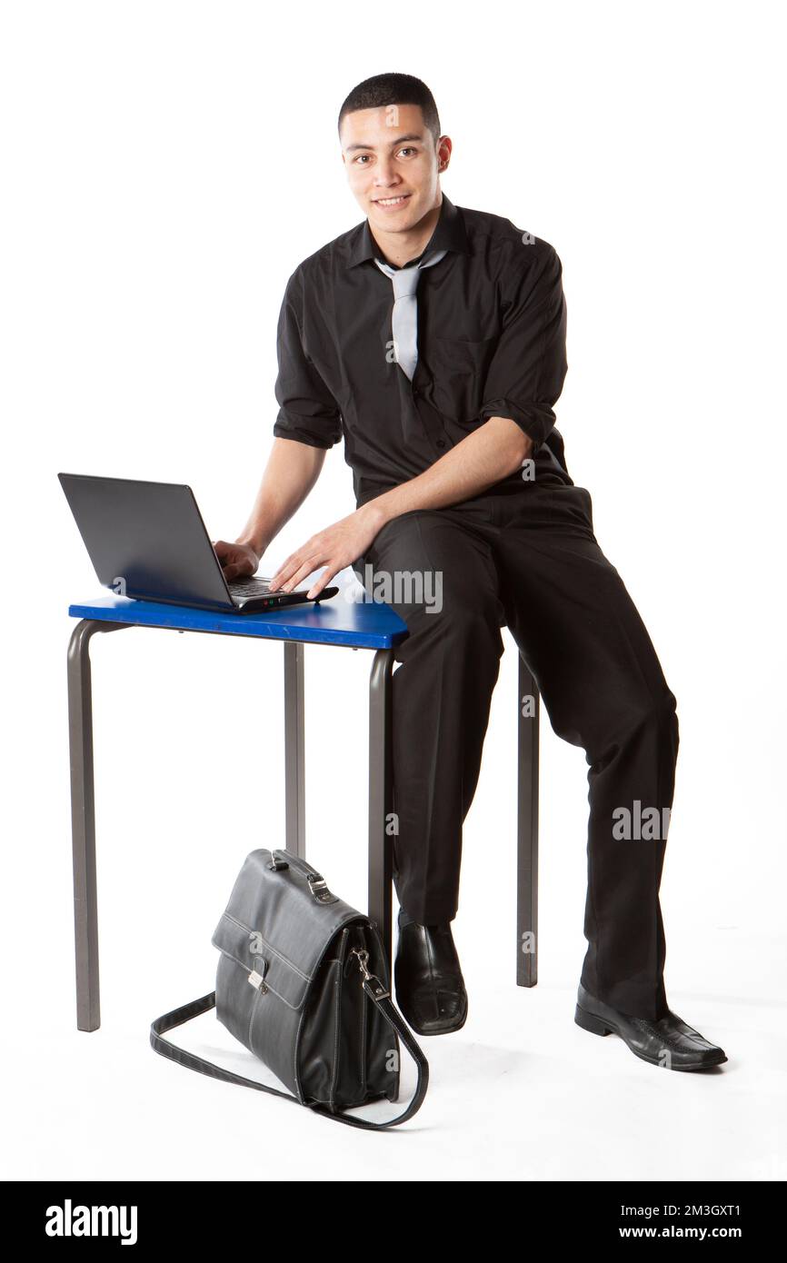 Teenager Schüler: Computerbenutzer. Ein verstorbener Teenager, der seinen Laptop benutzte, um seine Schularbeit zu recherchieren, volle Länge isoliert auf weiß. Aus einer Serie von Bildern. Stockfoto