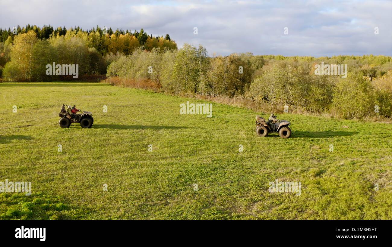 Grünes Sommerfeld. Clip. Ein Blick von einer Drohne für einen Spaziergang mit Quad auf einem hellen Feld in der Nähe eines Waldes. Hochwertige 4K-Aufnahmen Stockfoto