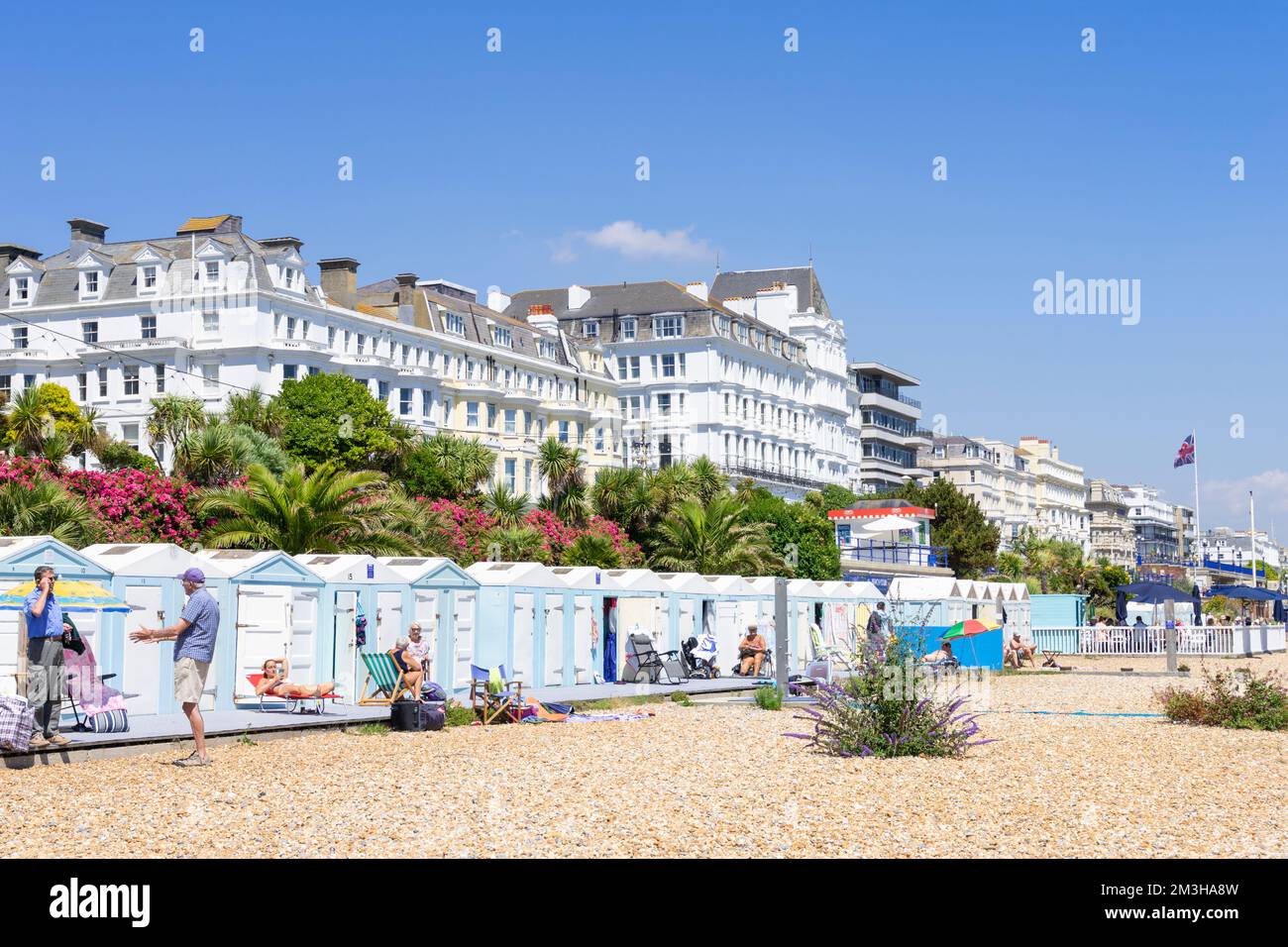 Eastbourne East Sussex Eastbourne Beach - Menschen, die die Sonne vor den Strandhütten am Eastbourne Beach Eastbourne East sussex England GB Europa genießen Stockfoto