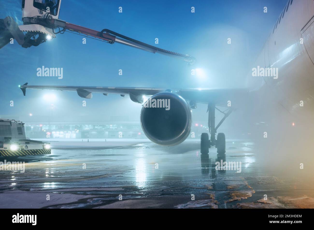 Enteisung des Flugzeugs vor dem Flug. Winternacht am Flughafen bei Schneefall. Stockfoto