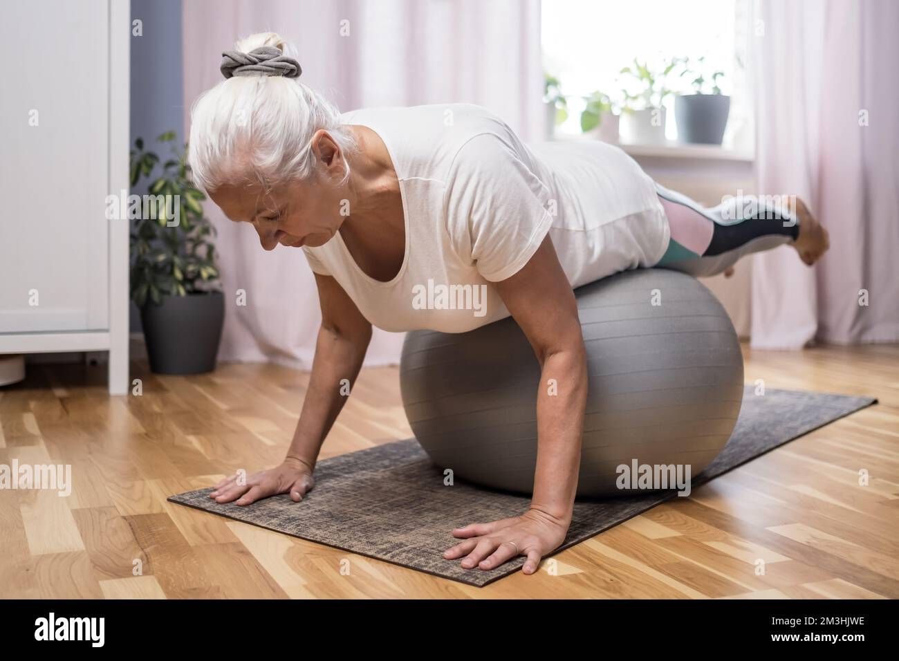 Eine Frau mittleren Alters in Plank-Position hält sich fit in ihrem Zuhause Stockfoto