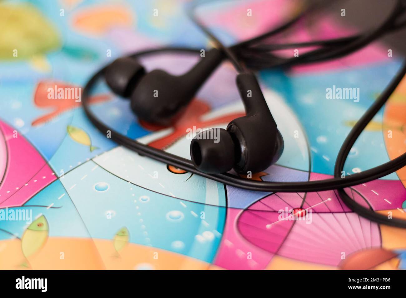 Schwarze kabelgebundene Ohrhörer, die auf einem farbigen Papaer liegen Stockfoto