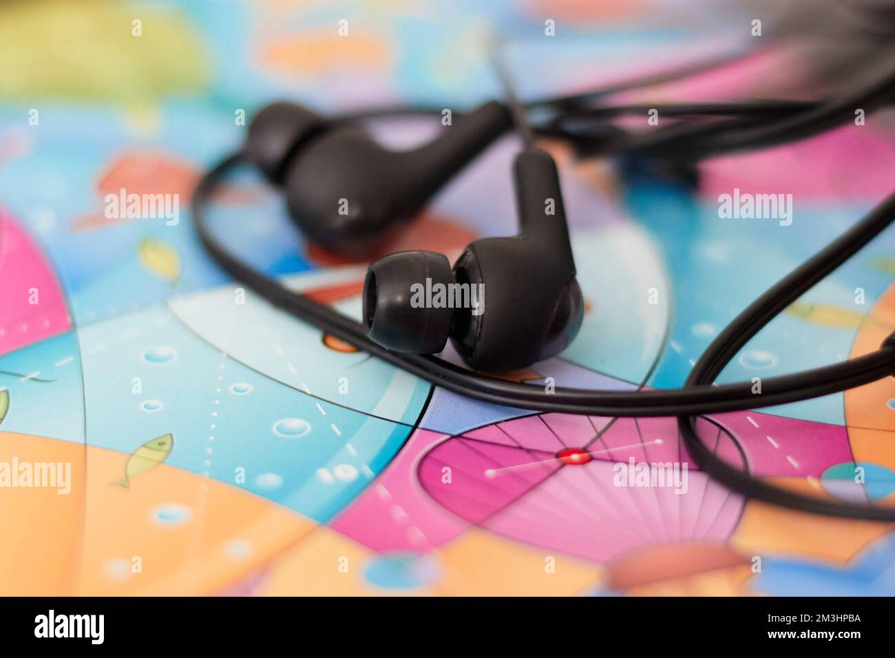 Schwarze kabelgebundene Ohrhörer, die auf einem farbigen Papaer liegen Stockfoto