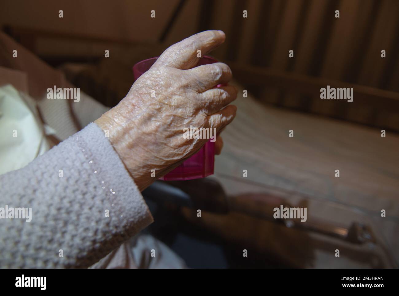 Die Hand einer älteren Frau hält ein Glas. Morbus Parkinson Stockfoto