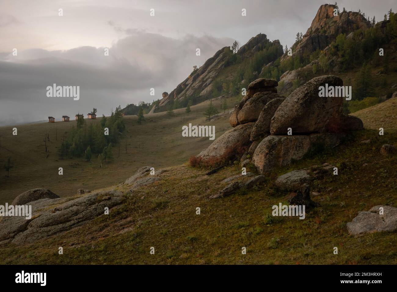 Winzige Häuser am nebligen Morgen, umgeben von Bäumen auf dem Bergrücken. Kleine Hütten auf dem Hügelkamm an einem nebligen Tag. Stockfoto