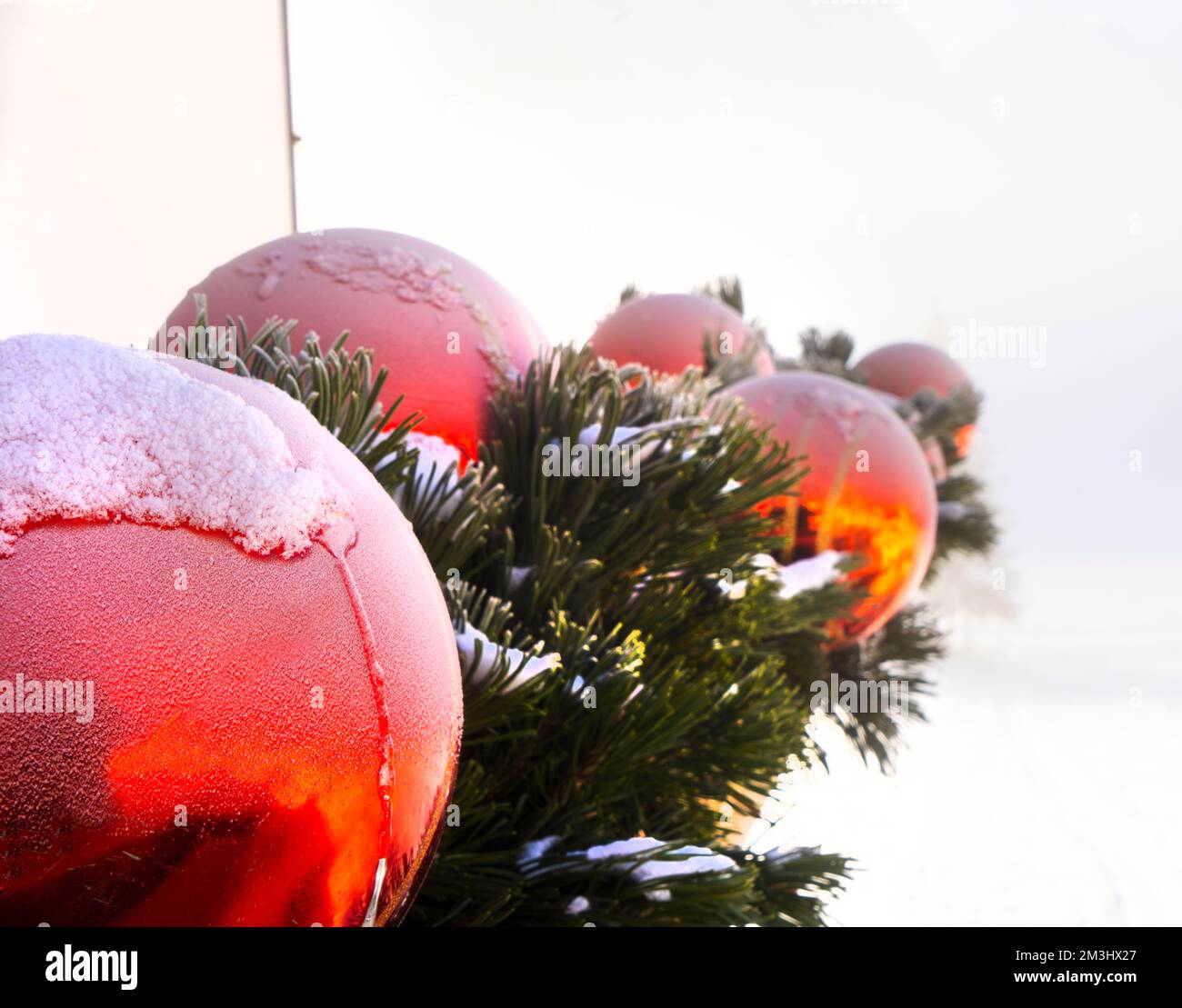 Details von Eis und Schnee über den roten Kugeln der Weihnachtsdekorationen Stockfoto