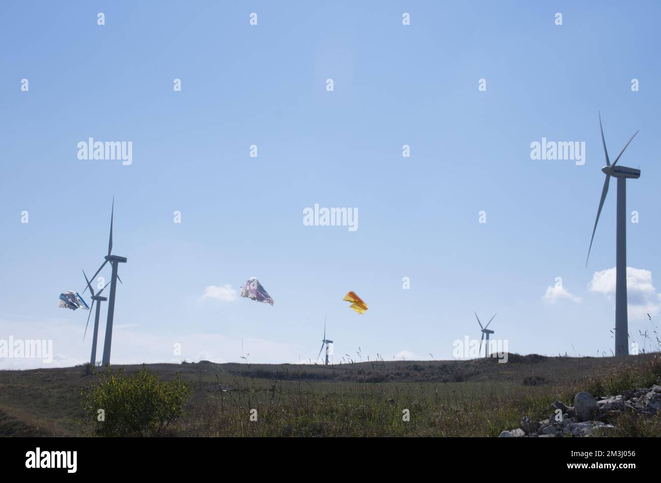 Farbenfrohe Drachen, angetrieben vom Wind mit Windturbinen, ein Symbol für Wind und erneuerbare Energie Stockfoto