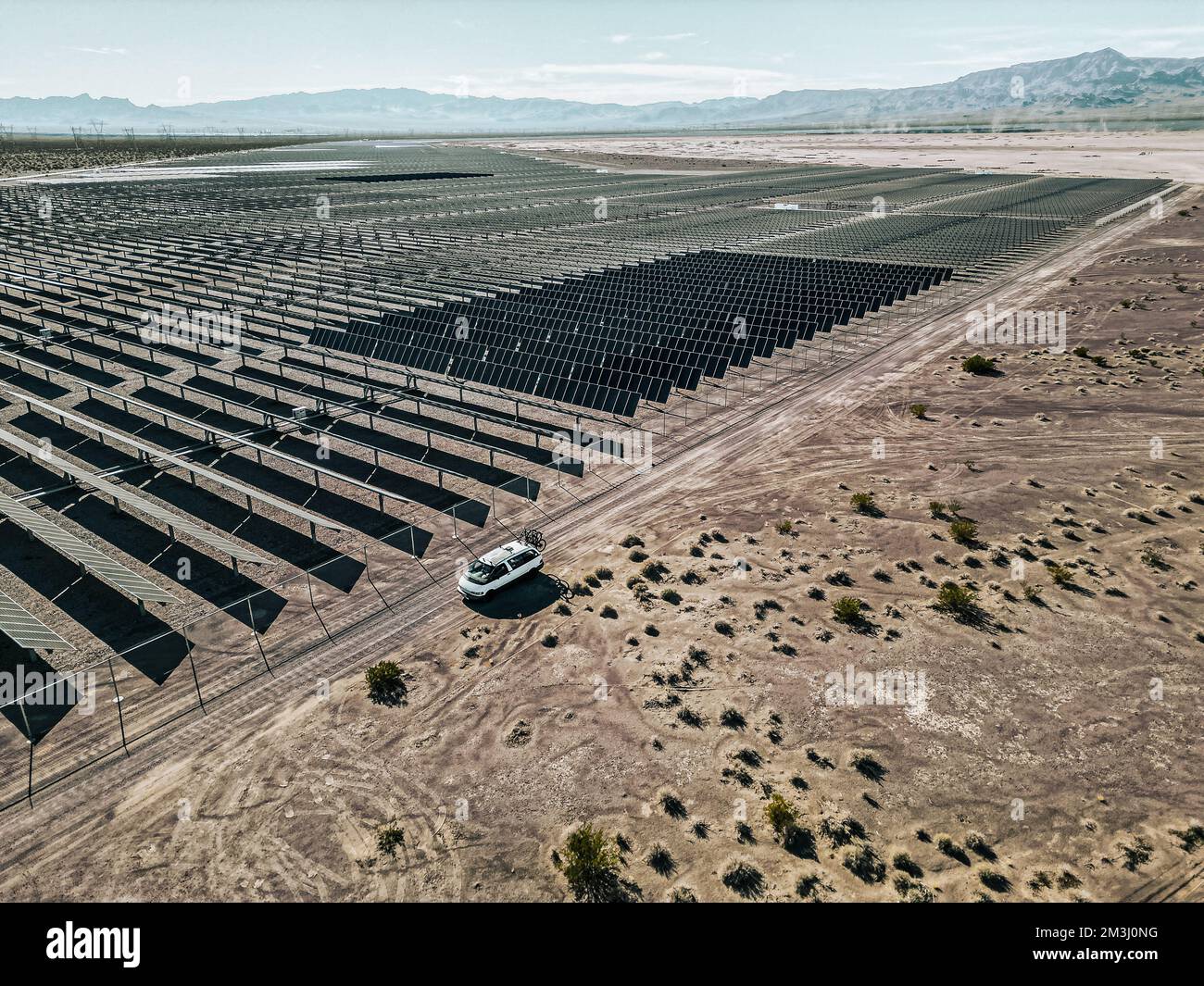 Off-Grid-Wohnmobil Wohnmobil Freizeitfahrzeug neben einer riesigen Solarfarm mit Solarmodulen, die Energie für die Stromversorgung einer Stadt erzeugen. Stockfoto