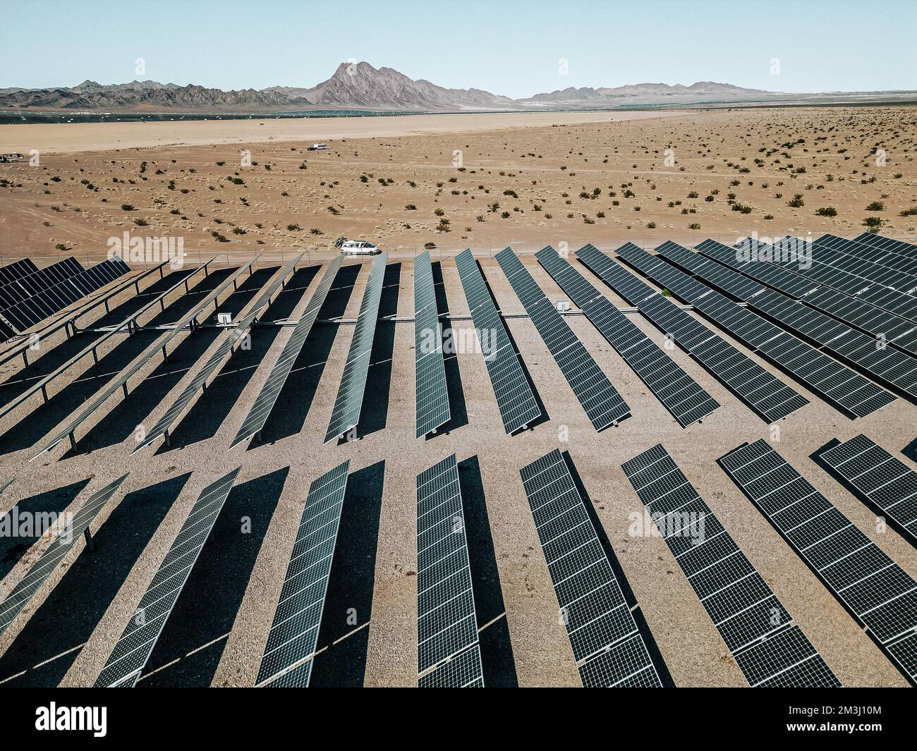 Off-Grid-Wohnmobil Wohnmobil Freizeitfahrzeug neben einer riesigen Solarfarm mit Solarmodulen, die Energie für die Stromversorgung einer Stadt erzeugen. Stockfoto