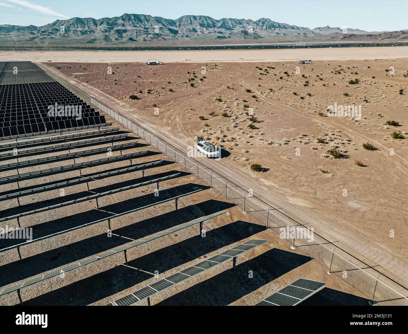 Off-Grid-Wohnmobil Wohnmobil Freizeitfahrzeug neben einer riesigen Solarfarm mit Solarmodulen, die Energie für die Stromversorgung einer Stadt erzeugen. Stockfoto