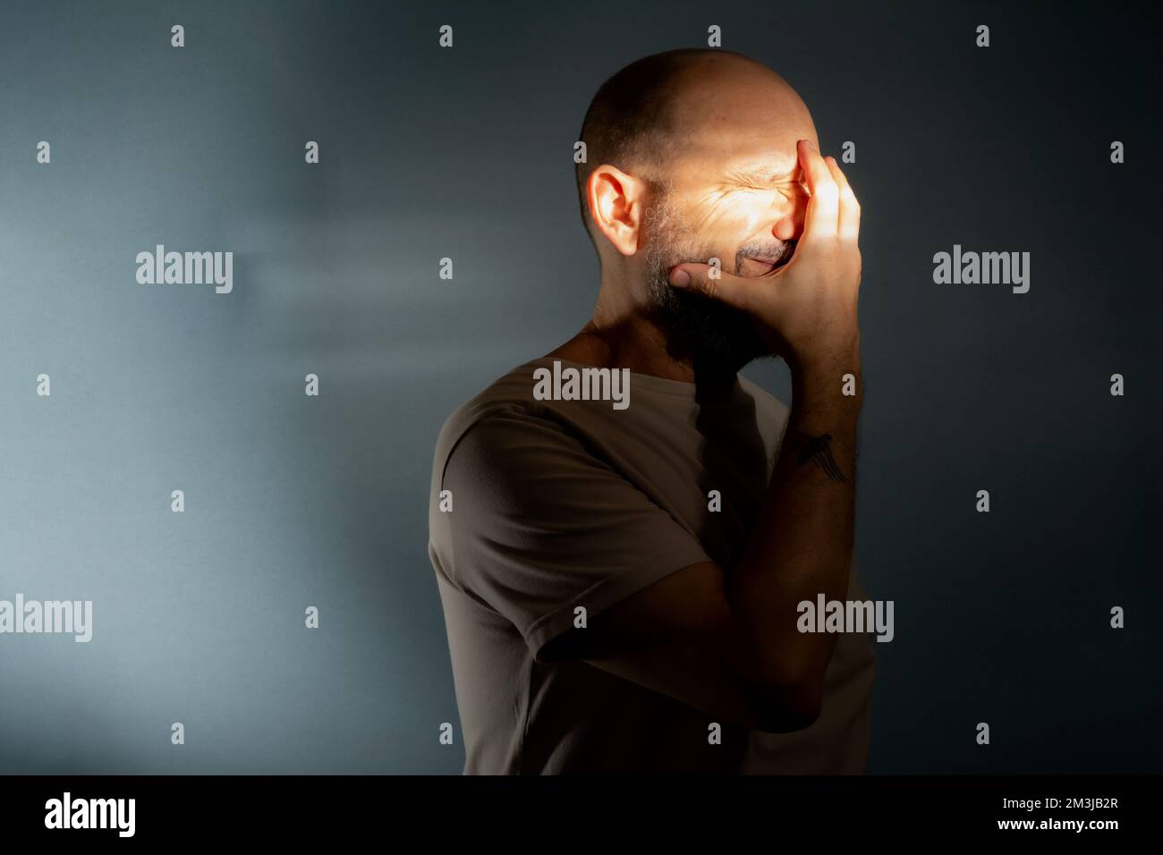 Depressiver Mann mittleren Alters mit Hand-im-Gesicht isoliert auf grauem Hintergrund, hat finanzielle Probleme oder leidet an Einsamkeit. Stockfoto