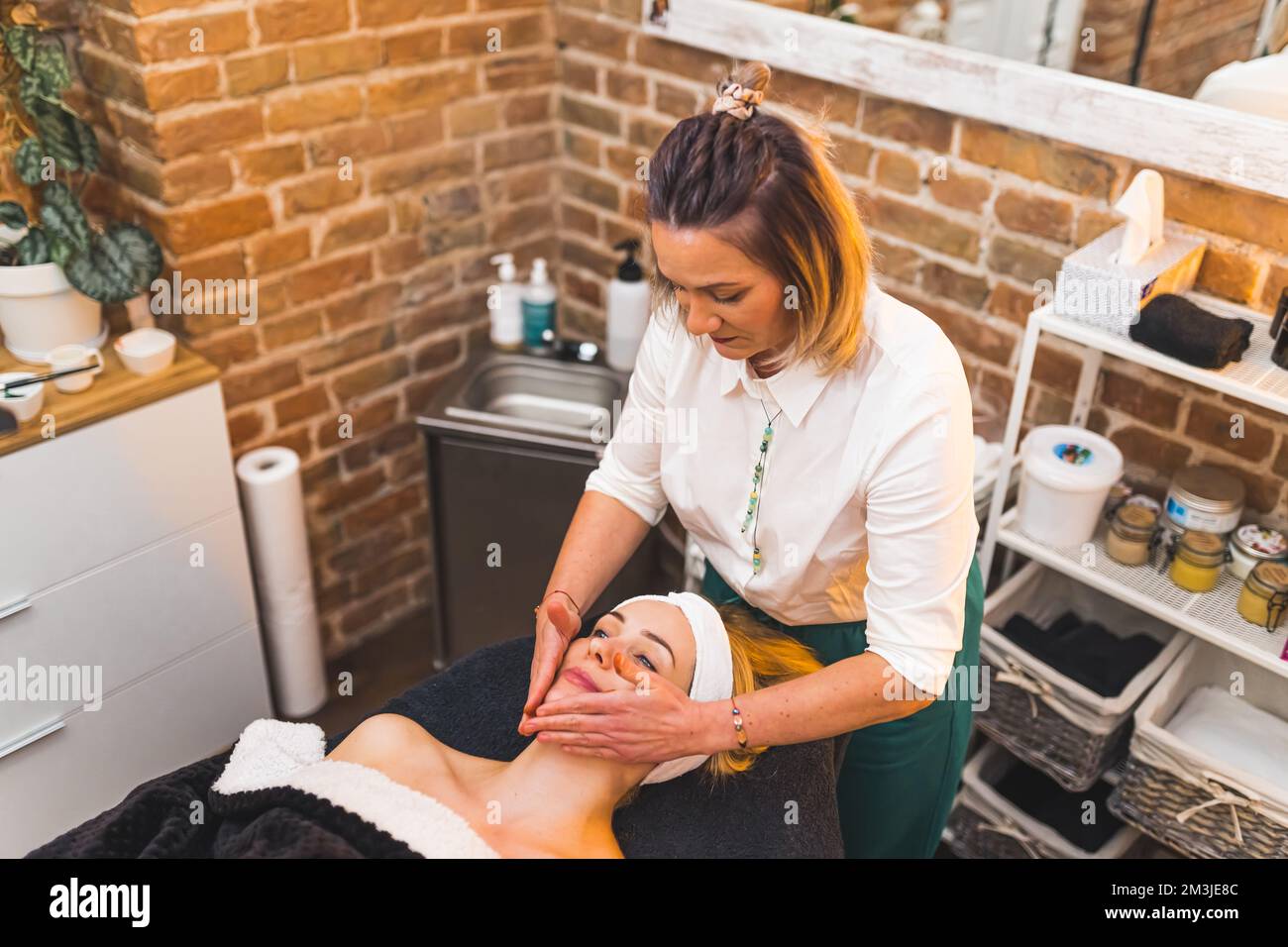 Junge Weiße bekommt eine Gesichtsmassage in einem Spa-Center, Selbstversorger-Konzept. Hochwertiges Foto Stockfoto