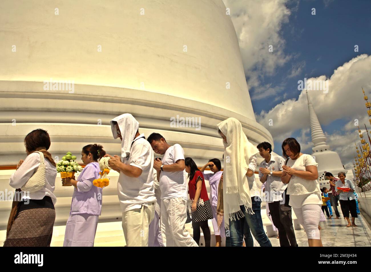 Eine Gruppe von Pilgern betet, während sie einen weißen, riesigen Stupa im Wat Phra Mahathat Woramahawihan umkreisen, dem wichtigsten buddhistischen Stupa in Nakhon Si Thammarat, der größten Provinz im Süden Thailands. Südostasien ist die Heimat zahlreicher religiöser Attraktionen, die mit Weltreligionen in Verbindung gebracht werden, wie Hinduismus, Buddhismus, Islam und Christentum. Es ist ein vielfältiges Gebiet, das durch buddhistische, hinduistische, islamische und christliche Religionen miteinander verschmolzen ist, die wiederum Spanier, Portugiesen, Chinesen, Niederländer, Briten, Französische und amerikanische kulturelle Einflüsse. Stockfoto