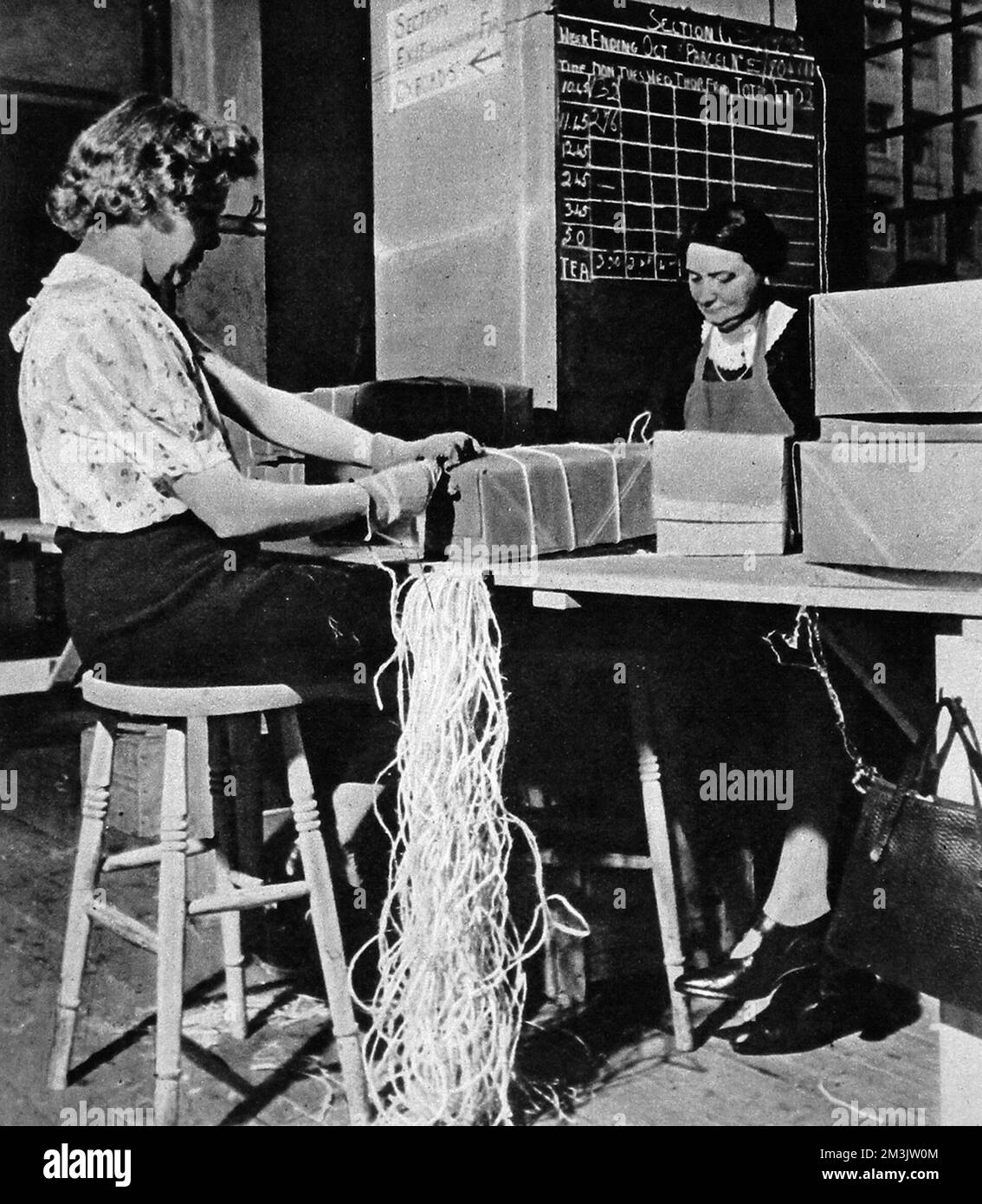 Ein Paket steht fast zur Versendung bereit. Freiwillige packten Pakete am Roten Kreuz-Hauptquartier, wo jede Woche Hektar Pappe und Meilen Schnur für die Verteilung von 70.000 Paketen an die britischen Kriegsgefangenen verwendet wurden. Stockfoto