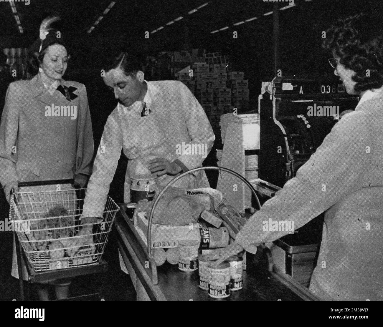Foto aus einem US-Supermarkt im Jahr 1948, „wo Großbritanniens Schlangen und Rationen unbekannt sind“, zeigt eine Frau, die an der Kasse bedient wird. Das Konzept des Supermarkts, in dem alle Arten von Waren an einem Ort ohne die Hilfe eines Ladenbesitzers gekauft und dann an der Kasse bezahlt werden konnten, wurde erstmals in Amerika eingeführt, wo es nach dem Zweiten Weltkrieg keine Rationierung gab Dieses Bild war eines von einer Serie, die in einem A&amp;P-Supermarkt aufgenommen wurde; Amerikas größte Kette begann 1937 und mit 1670 Supermärkten bis 1948. Datum: 1948 Stockfoto