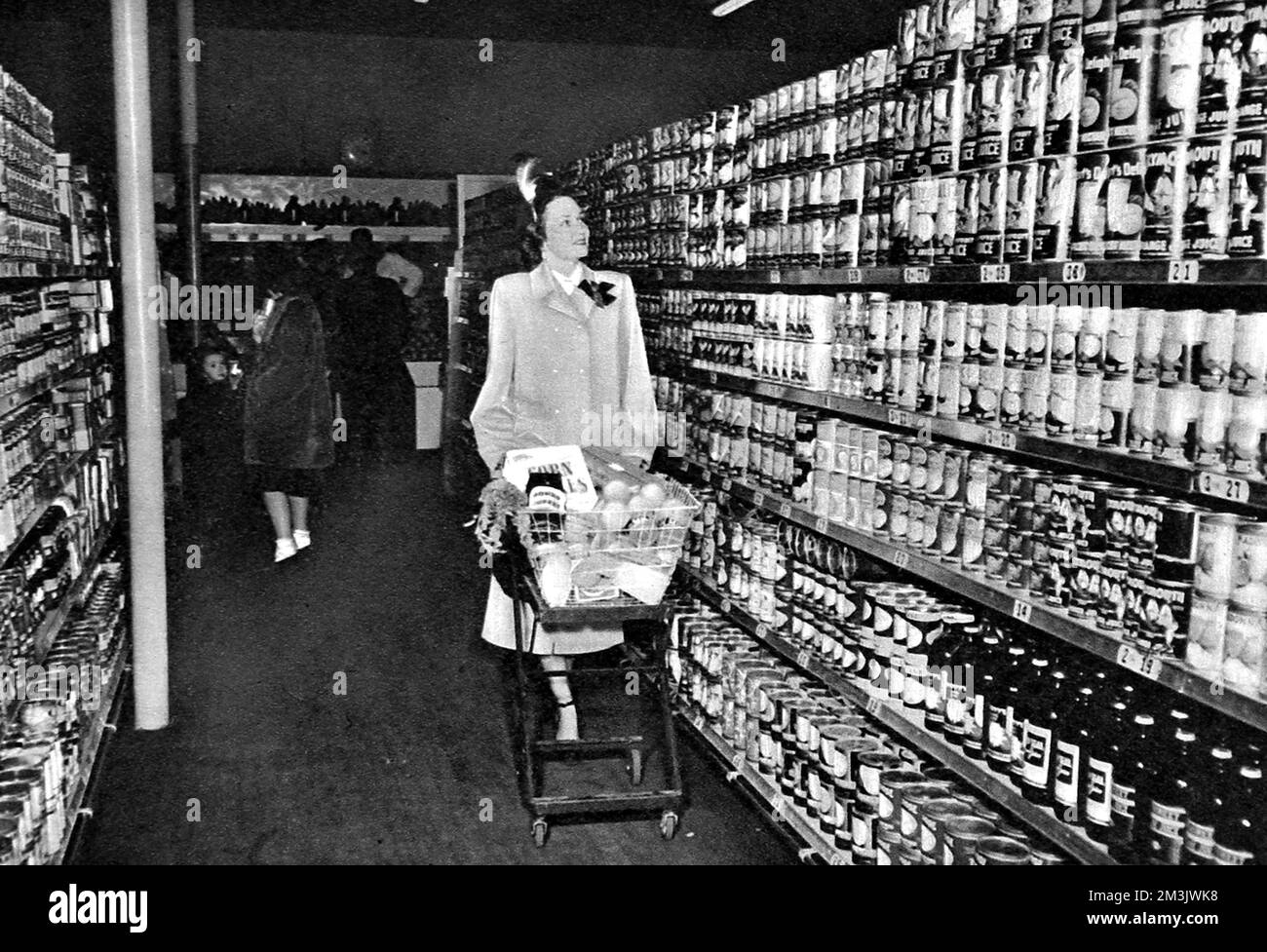 Eine amerikanische Hausfrau, die einen Einkaufswagen durch einen Supermarkt fährt; eine ungewöhnliche Seite für britische ILN-Leser, die 1948 noch mit der Rationierung zurechtkamen. Das Konzept des Supermarkts, in dem alle Arten von Waren an einem Ort ohne die Hilfe eines Ladenbesitzers gekauft und dann an der Kasse bezahlt werden konnten, wurde erstmals in Amerika eingeführt, wo es nach dem Zweiten Weltkrieg keine Rationierung gab Dieses Bild war eines von einer Serie, die in einem A&amp;P-Supermarkt aufgenommen wurde; Amerikas größte Kette begann 1937 und mit 1670 Supermärkten bis 1948. 1948 Stockfoto