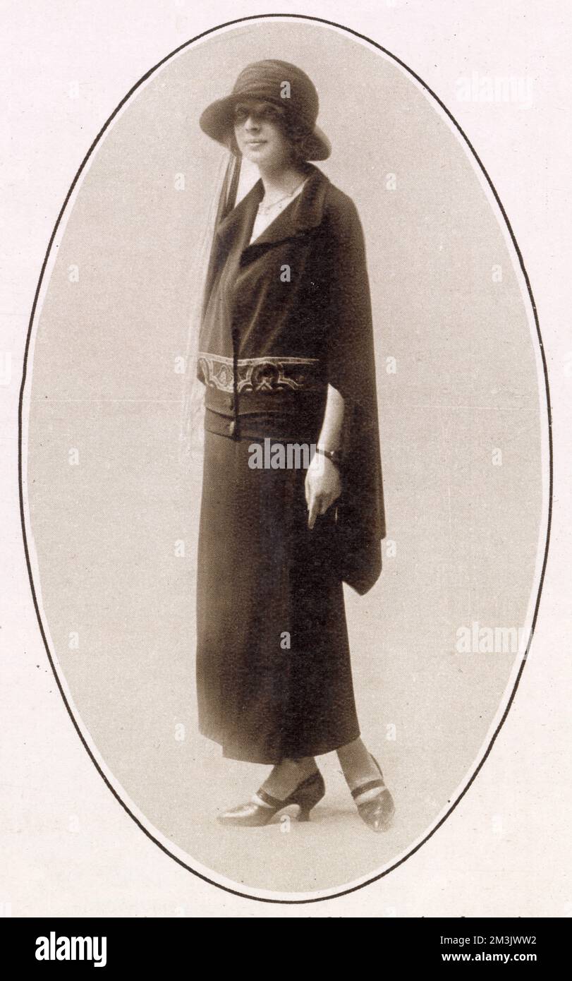 Ein attraktiver 3-teiliger Anzug mit einem Doppelgürtel, der die Kombination aus Mantel und Umhang fixiert. Stockfoto