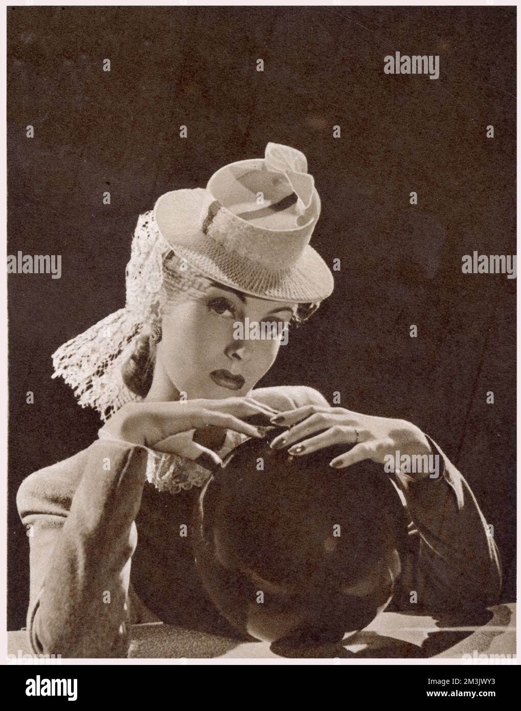 Ein weißer Hut mit Wabenmuster und einem magentafarbenen Band, besetzt mit einem weißen Spitzenschleier, 1939. Stockfoto