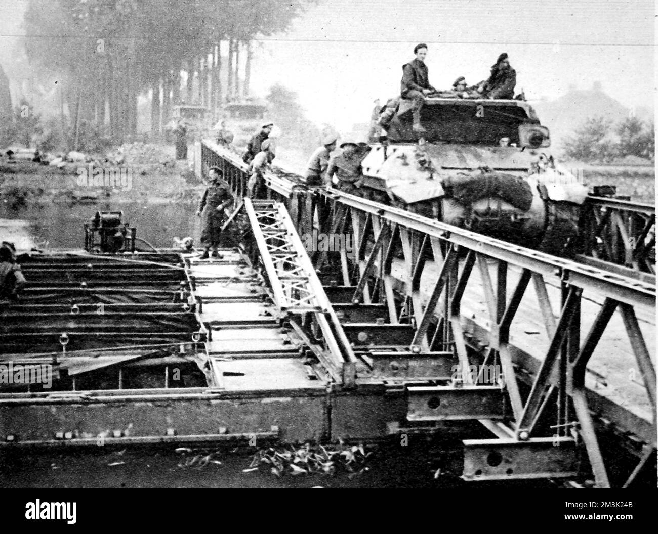 Das Foto zeigt britische Panzer und selbstfahrende Gewehre, die eine Bailey-Brücke überqueren, Holland, 1944. Diese Brücke wurde von britischen Ingenieuren während der Operation „Market Garden“ über einen Kanal gebaut, als das 30. Korps in Richtung Arnheim eilte. 1944 Stockfoto