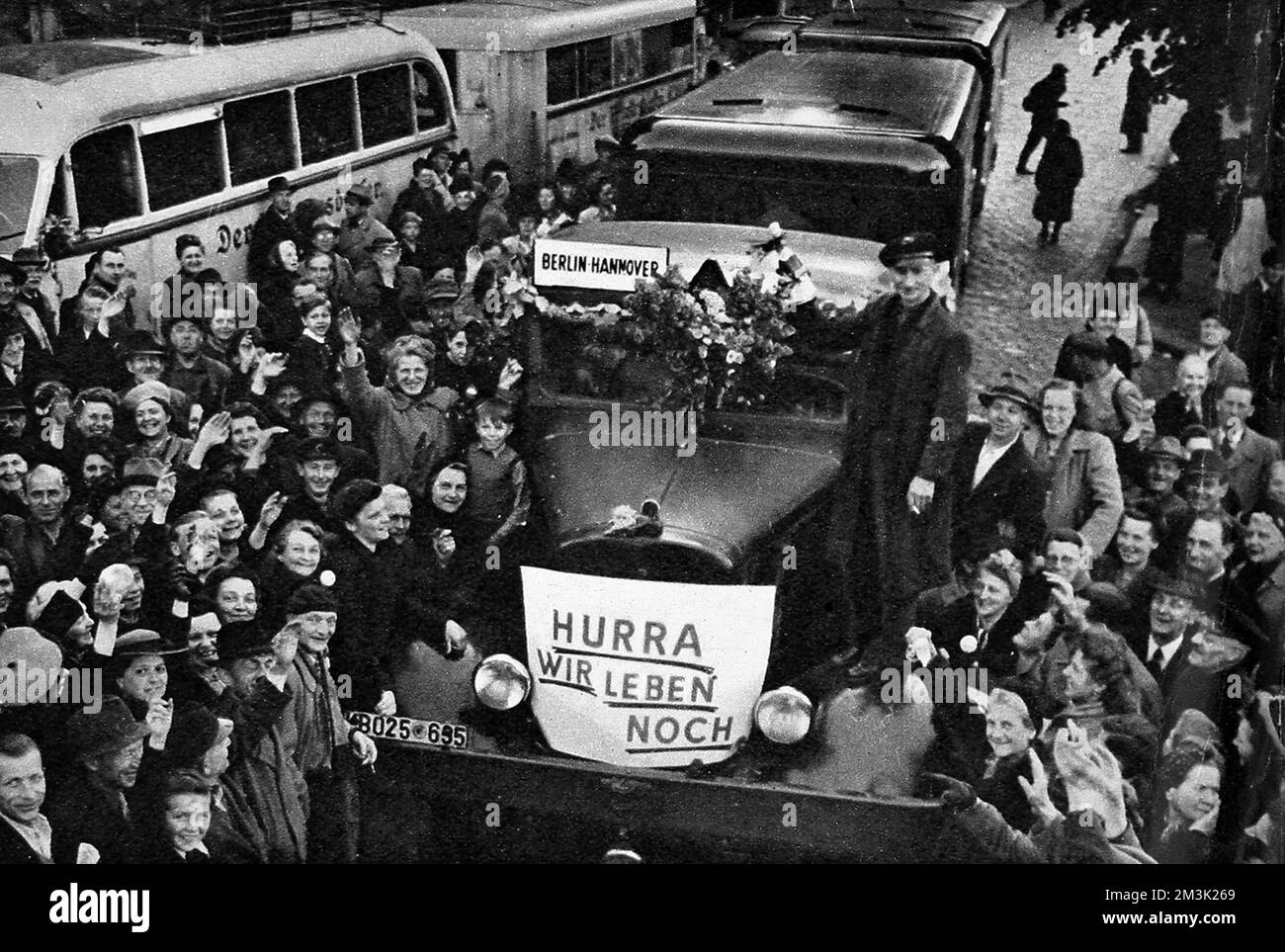 Das Foto zeigt den ersten zivilen Bus, der nach dem Ende der Sowjetblockade am 1949. Mai West-Berlin verlassen hat. Der Bus fuhr nach Hannover und trug stolz das Banner „Hurra, wir leben noch“ auf seiner Vorderseite. Zwischen April 1948 und Mai 1949 verhängte Josef Stalin, Führer der UdSSR, eine Landblockade für Lieferungen von Westeuropa nach Westberlin. Als Reaktion darauf organisierten die britische und die amerikanische Regierung eine enorme Luftbrücke, um den 2,5 Millionen Einwohnern Westberlins Nahrungsmittel und andere Hilfsgüter zu liefern. Nach einem Jahr räumte Stalin die Niederlage ein und hob die Blockade auf. Datum: 1949 Stockfoto