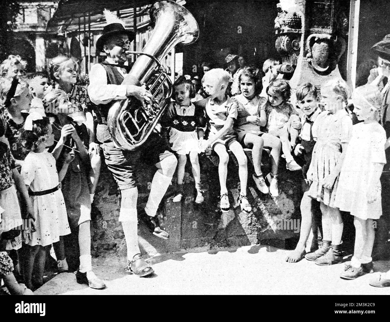 Eine Gruppe von Kindern hört einem Mann zu, der in Berlin Tuba spielt, kurz nach dem Ende des Zweiten Weltkriegs in Europa, August 1945. Datum: 1945 Stockfoto