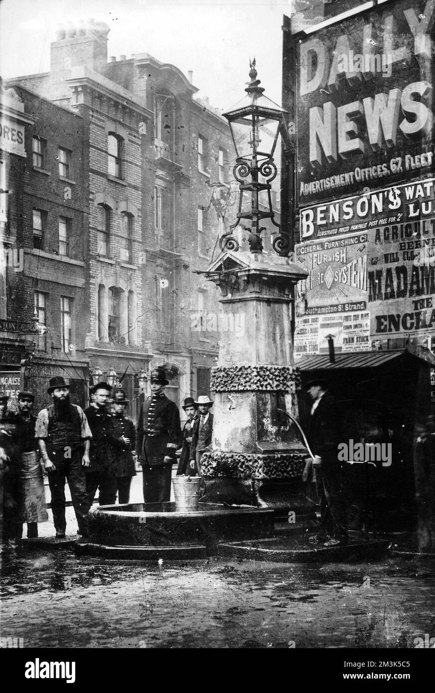 Eine Menge Männer, darunter ein Polizist, stehen um die Old Aldgate Pump in London. Datum: c.1870er Stockfoto