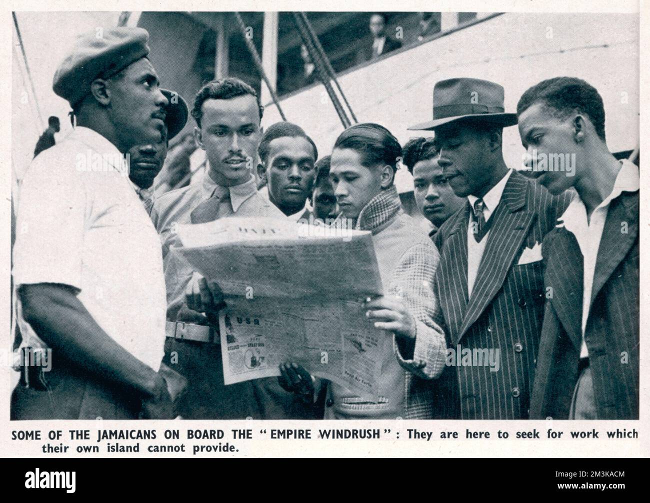 Jamaikanische Männer an Bord des Empire Windrush, die nach Großbritannien gekommen sind, um Arbeit zu suchen; einige der Männer, schlau gekleidet in Jacken und Krawatten, lesen eine Zeitung. Juni 1948 Stockfoto