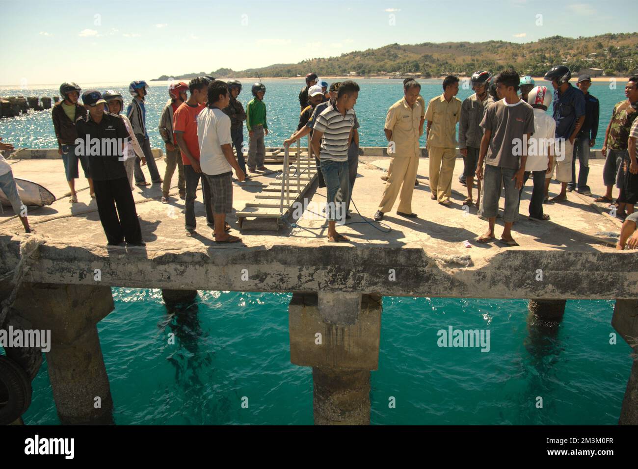 Menschen, die auf der Anlegestelle warten, während eine Fähre von Kupang anlegt, werden im Hafen von Baa, Rote Island, East Nusa Tenggara, Indonesien vor Anker gelegt. Laut Noah Kaiser (Mortenson Center in Global Engineering, University of Colorado) und Christina K. Barstow (Bridges to Prosperity, Denver) ist die ländliche Verkehrsinfrastruktur in isolierten Gemeinden in Ländern mit niedrigem und mittlerem Einkommen weltweit ein entscheidender Faktor für die Entwicklung. Sie veröffentlichte am 14. Februar 2022 ein wissenschaftliches Dokument über Nachhaltigkeit. Zugriff über MDPI. Stockfoto
