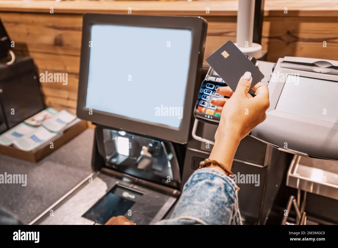 Die Käuferin belastet das POS-Terminal mit einer Kreditkarte, um die Einkäufe an der Self-Service-Kasse zu bezahlen Stockfoto