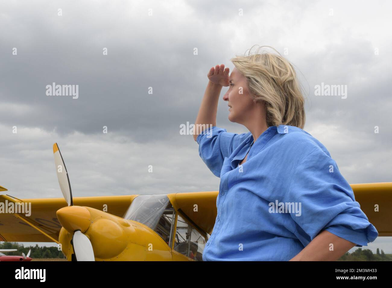 Gewitterwolken. Blonde Frau im Hintergrund einer gelben Ebene der Vergangenheit Stockfoto