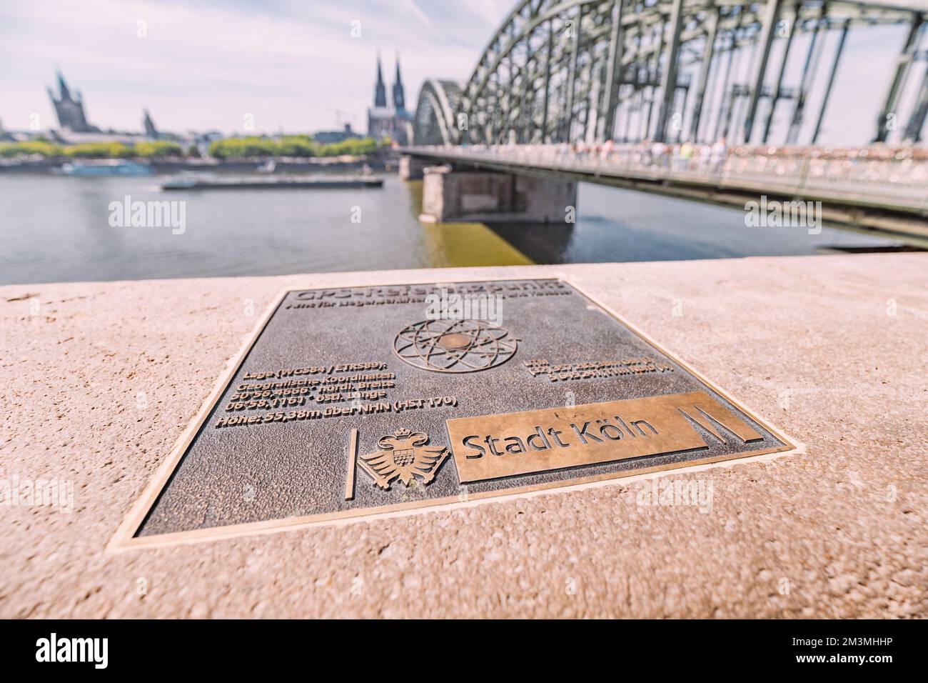 30. Juli 2022, Köln, Deutschland: Schild mit GPS-Koordinaten der Stadt und malerischem Blick auf die Rheinbrücke und den Kölner Dom Stockfoto