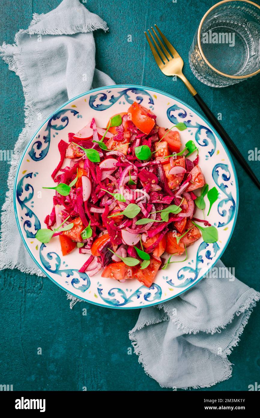 Wintersalat: Eingelegter Rotkohlsalat mit Rettich, Tomaten, Zwiebeln und Winterportulak. Vegetarisches gesundes Essen. Stockfoto