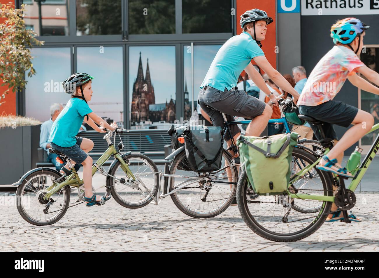 29. Juli 2022, Köln, Deutschland: Eine Sportfamilie - ein Vater mit einem Kind fährt Fahrrad durch die Straßen einer alten europäischen Stadt Stockfoto